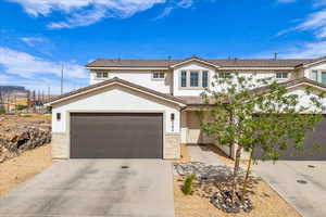 Traditional home with a garage, stucco siding, driveway, and stone siding