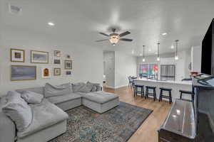 Living room with visible vents, a ceiling fan, light wood-style floors, and recessed lighting