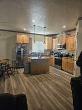 Kitchen featuring a kitchen island, stainless steel appliances, a textured ceiling, and dark wood finished floors