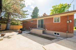 Back of house with fence, a patio area, and brick siding