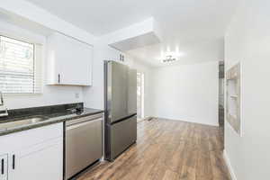 Kitchen with a sink, wood finished floors, white cabinets, and stainless steel appliances