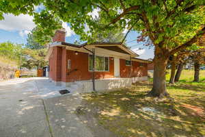 View of home's exterior with concrete driveway, brick siding, and a chimney