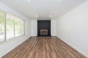 Unfurnished living room with recessed lighting, baseboards, a fireplace, and dark wood-style flooring