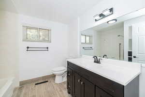 Full bathroom with wood finish floors, vanity, toilet,  shower combination, and visible vents