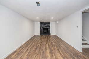 Unfurnished living room with baseboards, a brick fireplace, recessed lighting, and wood finished floors
