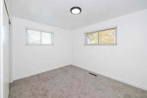 Spare room featuring baseboards, visible vents, and carpet