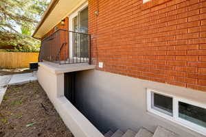 View of side of property featuring brick siding, fence, and cooling unit