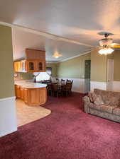 Carpeted living room featuring ceiling fan, ornamental molding, a textured ceiling, and lofted ceiling