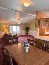 Carpeted dining room featuring wainscoting, ceiling fan, vaulted ceiling, and a textured ceiling