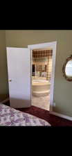 Bedroom featuring carpet flooring, baseboards, tile patterned floors, and connected bathroom