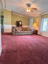 Living room with crown molding, a ceiling fan, and carpet flooring