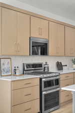 Kitchen with light countertops, appliances with stainless steel finishes, tasteful backsplash, and light brown cabinets