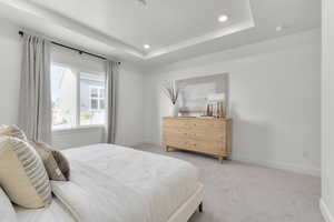 Bedroom with recessed lighting, baseboards, light carpet, and a tray ceiling