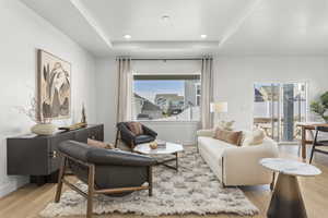Living area featuring baseboards, a tray ceiling, a wealth of natural light, and wood finished floors