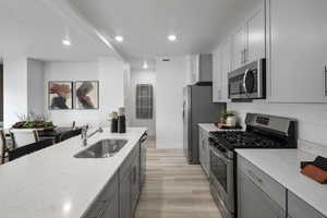 Kitchen featuring a textured ceiling, gray cabinets, appliances with stainless steel finishes, and a sink