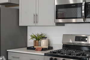 Kitchen with light stone counters, white cabinets, and stainless steel appliances