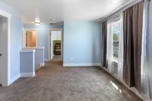 Carpeted spare room featuring baseboards
