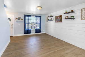 Unfurnished dining area featuring baseboards, wood walls, and wood finished floors