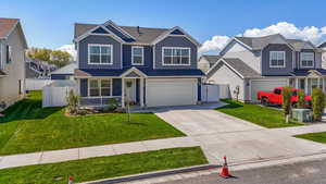 View of front facade with a garage, board and batten siding, fence, and driveway