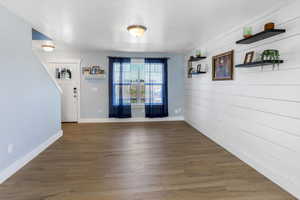 Unfurnished dining area featuring baseboards, wood walls, and wood finished floors