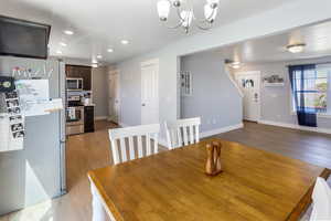 Dining room with baseboards, recessed lighting, light wood-style flooring, and a notable chandelier
