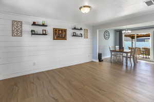 Unfurnished dining area featuring baseboards, a notable chandelier, visible vents, and wood finished floors