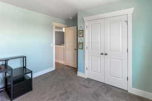 Carpeted bedroom with baseboards and a closet