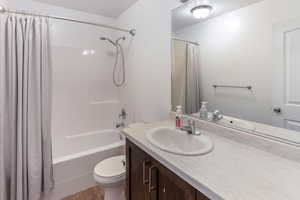 Bathroom with vanity, toilet, wood finished floors, and shower / tub combo with curtain