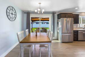 Dining area featuring baseboards, a notable chandelier, visible vents, and light wood-style floors