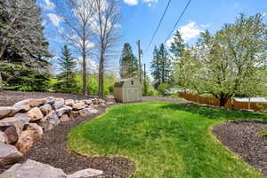 View of yard featuring a shed, an outbuilding, and fence