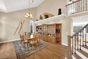 Dining space with high vaulted ceiling, baseboards, stairway, and light wood-type flooring