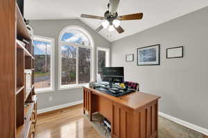 Office space with visible vents, lofted ceiling, baseboards, ceiling fan, and light wood finished floors