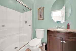 Bathroom featuring vanity, toilet, baseboards, and a stall shower