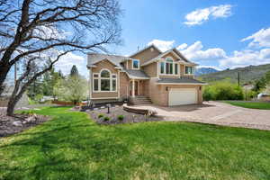 View of front facade featuring driveway, a front yard, a garage, a mountain view, and stucco siding