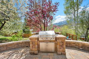 View of patio featuring a mountain view, fence, grilling area, and an outdoor kitchen