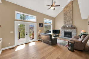 Living area featuring french doors, a ceiling fan, high vaulted ceiling, baseboards, and light wood-style flooring