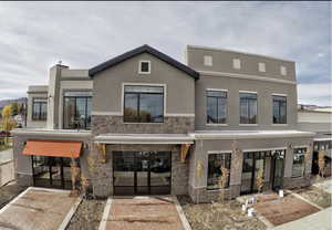 Rear view of property featuring french doors, stone siding, and stucco siding