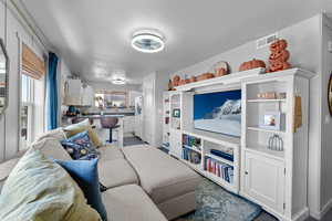 Living room with a textured ceiling and visible vents