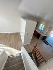 Stairs with a textured ceiling, vaulted ceiling, and wood finished floors