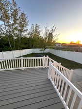 Deck at dusk with a lawn and a fenced backyard