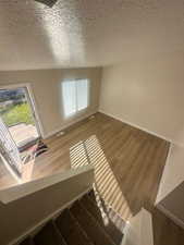 Interior space featuring visible vents, stairs, wood finished floors, baseboards, and a textured ceiling