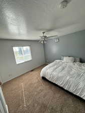 Carpeted bedroom featuring baseboards, ceiling fan, a textured ceiling, and visible vents