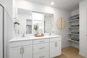 Full bathroom with double vanity, a walk in closet, a sink, and wood finished floors