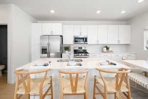 Kitchen featuring a sink, appliances with stainless steel finishes, light wood-style floors, and recessed lighting