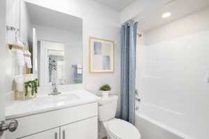 Full bathroom featuring vanity, shower / tub combo with curtain, and toilet