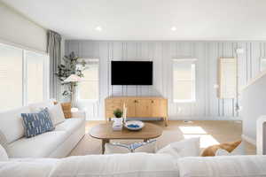 Living area featuring visible vents, light wood-type flooring, baseboards, a decorative wall, and recessed lighting