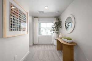 Hallway with baseboards, carpet floors, a textured ceiling, and visible vents