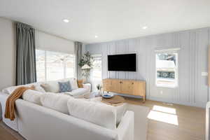 Living area with recessed lighting, light wood finished floors, and a decorative wall