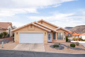 Ranch-style home featuring an attached garage, stucco siding, a mountain view, a tiled roof, and driveway