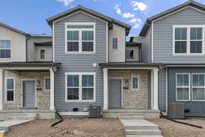 Townhome / multi-family property featuring central AC and stone siding